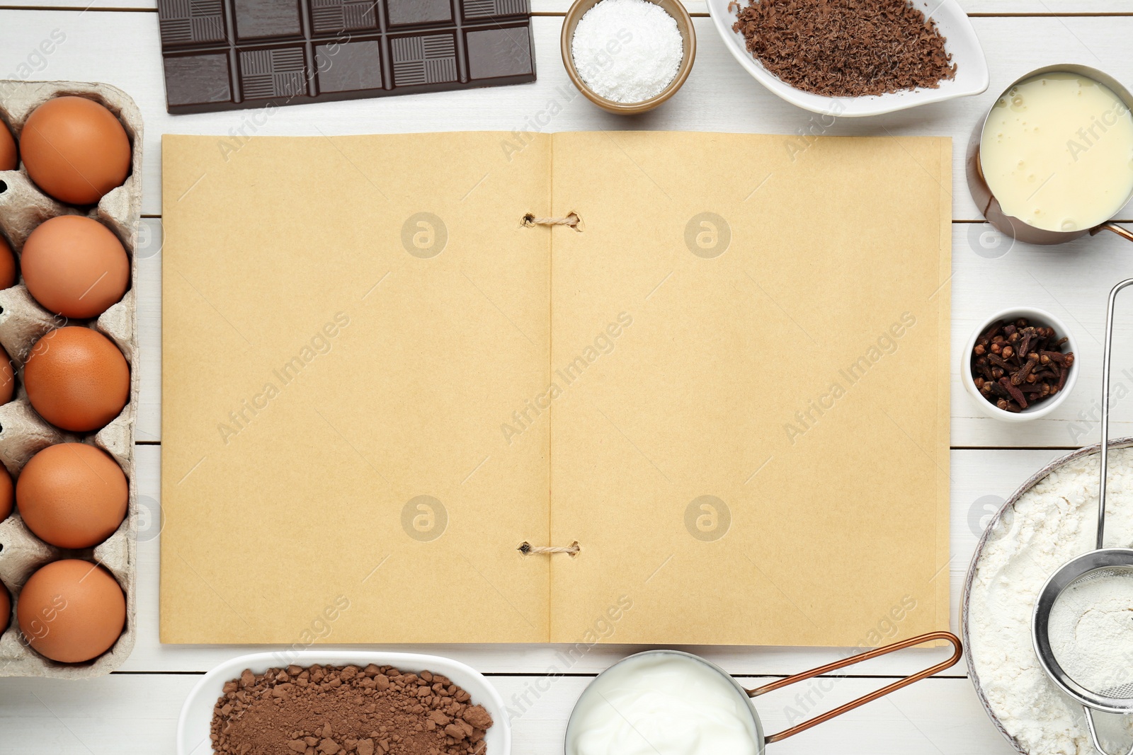 Photo of Blank recipe book surrounded by different ingredients on white wooden table, flat lay. Space for text