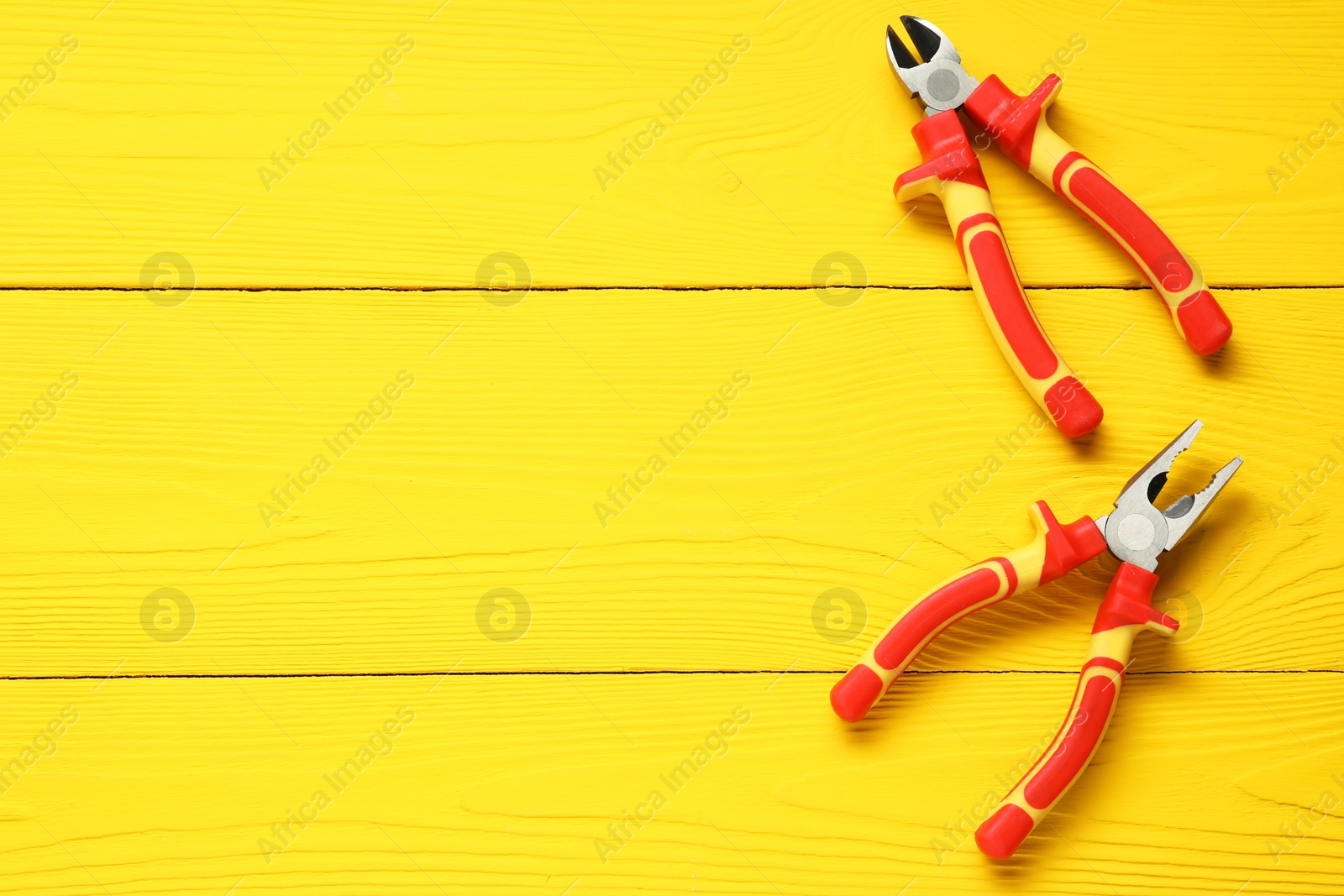 Photo of Pliers on yellow wooden table, flat lay. Space for text