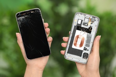 Woman holding damaged smartphone on blurred green background, closeup. Device repairing