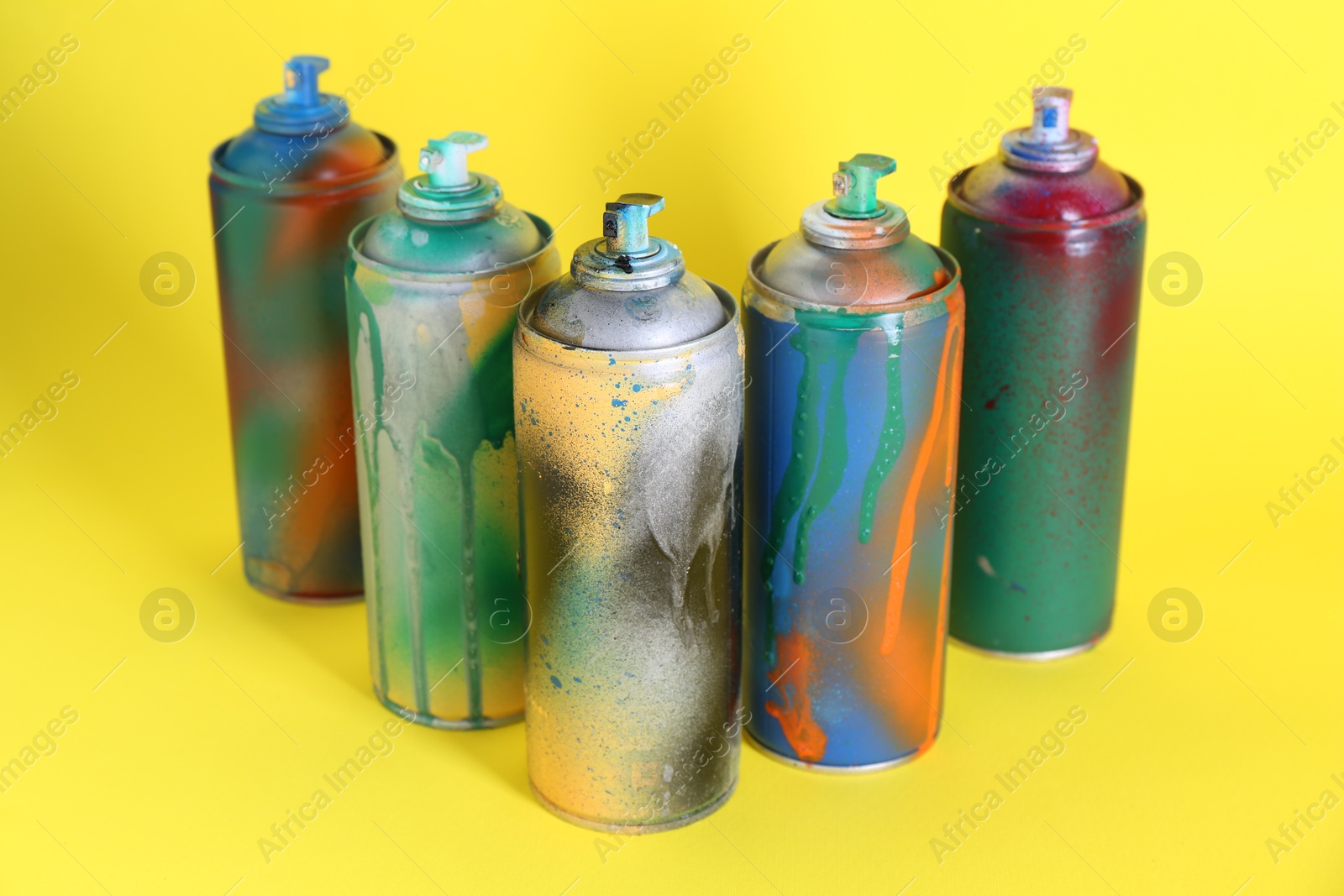 Photo of Many spray paint cans on yellow background