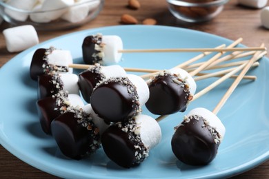 Photo of Delicious marshmallows covered with chocolate and crushed nuts on plate, closeup