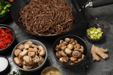 Photo of Wok with noodles, chicken and other products on grey table