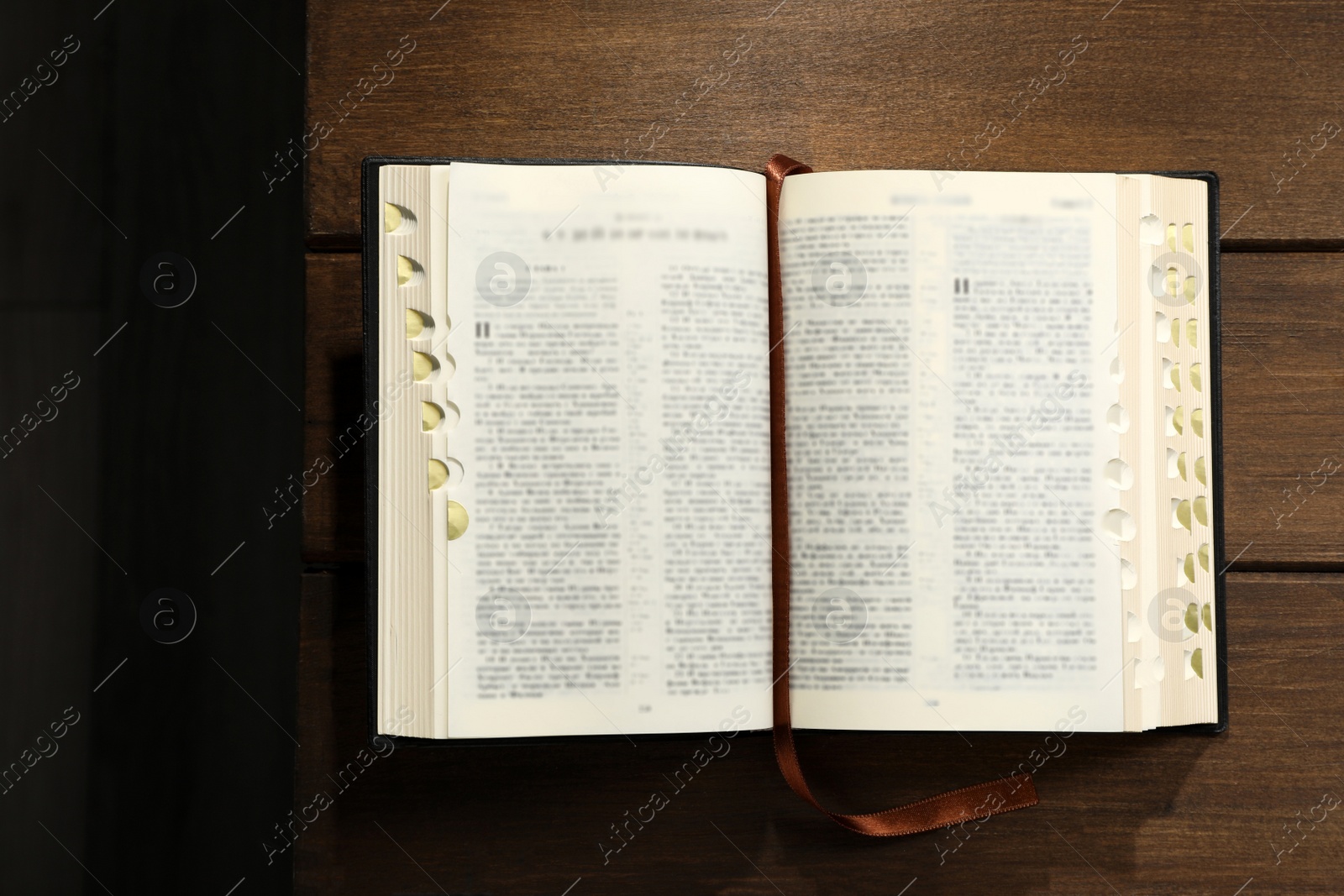 Photo of Open Bible on wooden table, top view. Christian religious book