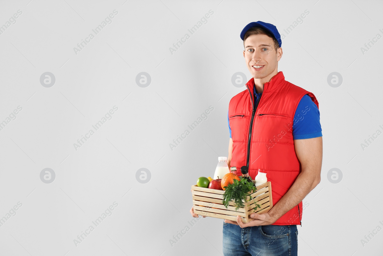 Photo of Courier with fresh products on light background, space for text. Food delivery service