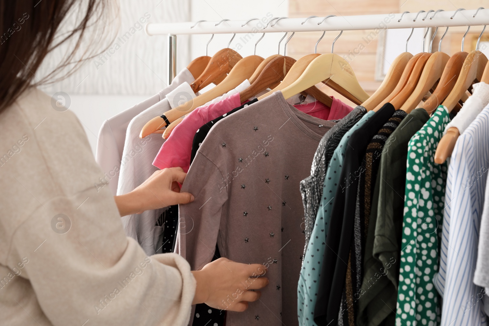 Photo of Woman choosing clothes from wardrobe rack, closeup