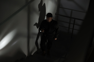 Male security guard with flashlight going up stairs in darkness