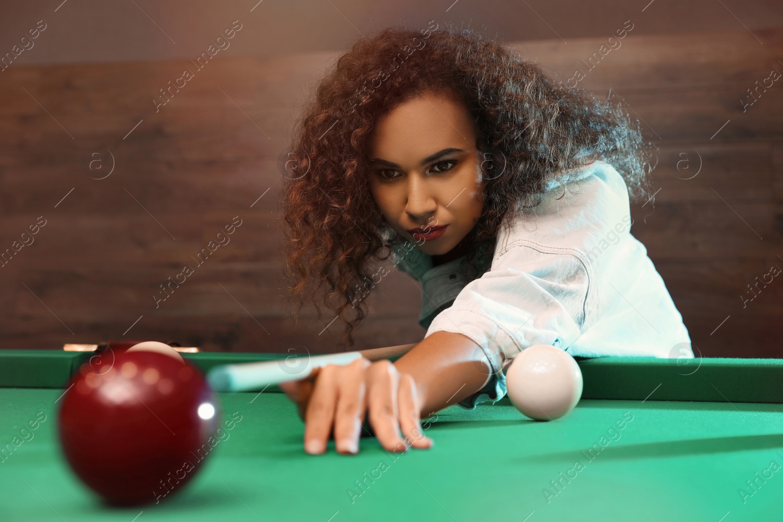 Photo of Young African-American woman playing Russian billiard indoors