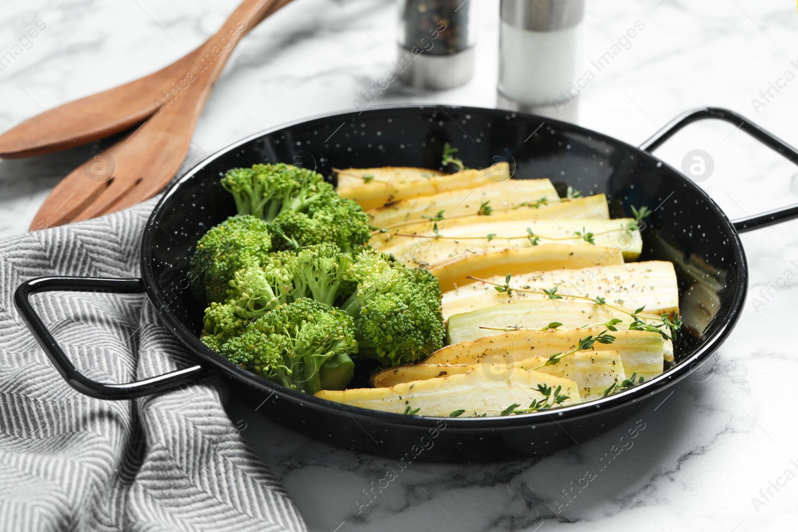 Photo of Raw white carrot and broccoli in frying pan on white marble table, closeup