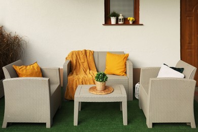 Beautiful rattan garden furniture, soft pillows, blanket and houseplant outdoors