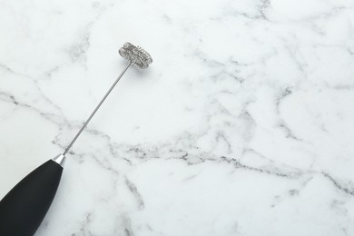 Black milk frother wand on white marble table, top view. Space for text