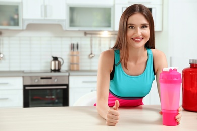 Photo of Young woman with bottle of protein shake in kitchen