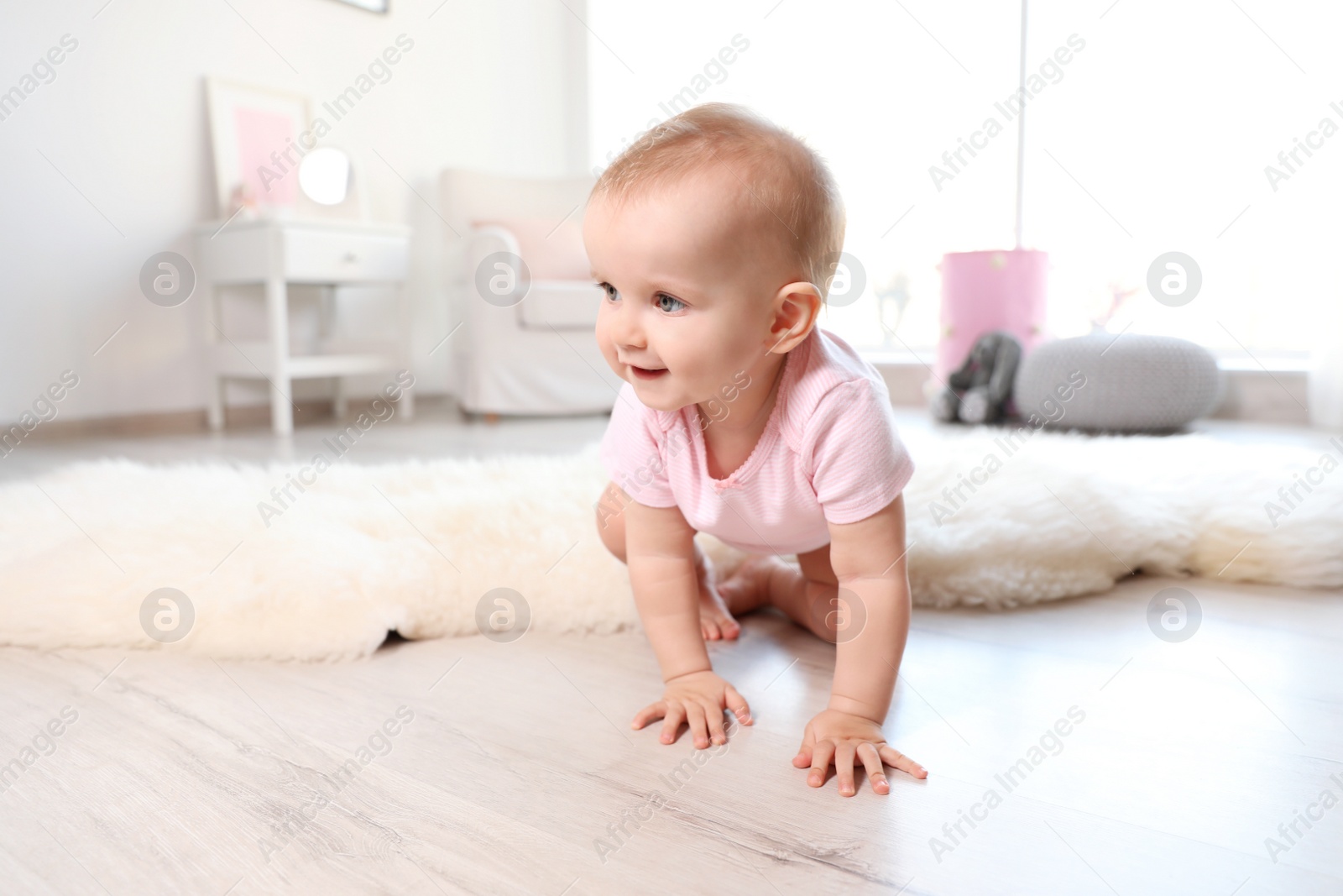 Photo of Cute baby girl crawling on floor in room