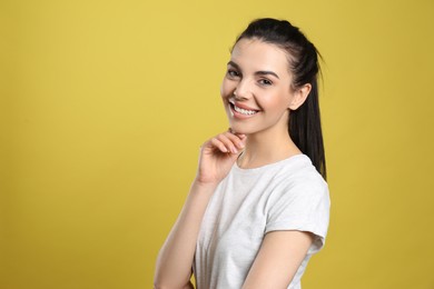 Photo of Portrait of happy young woman with beautiful black hair and charming smile on yellow background, space for text