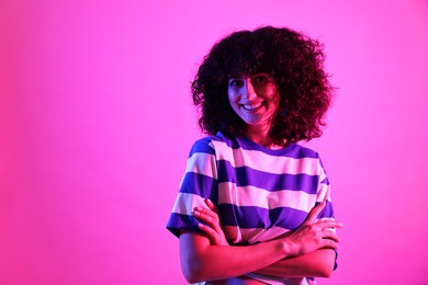 Photo of Beautiful young woman posing on color background in neon lights. Space for text