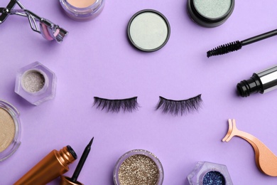 Flat lay composition with magnetic eyelashes and accessories on violet background