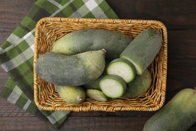 Photo of Green daikon radishes in wicker basket on wooden table, top view