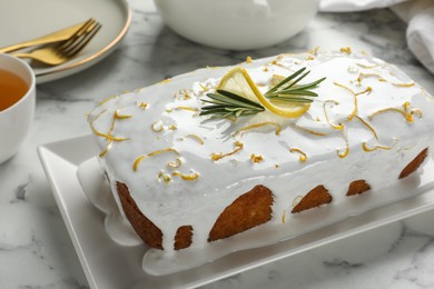 Photo of Tasty lemon cake with glaze on white marble table, closeup