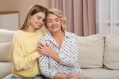 Photo of Young woman with her mom on sofa at home. Happy Mother's Day