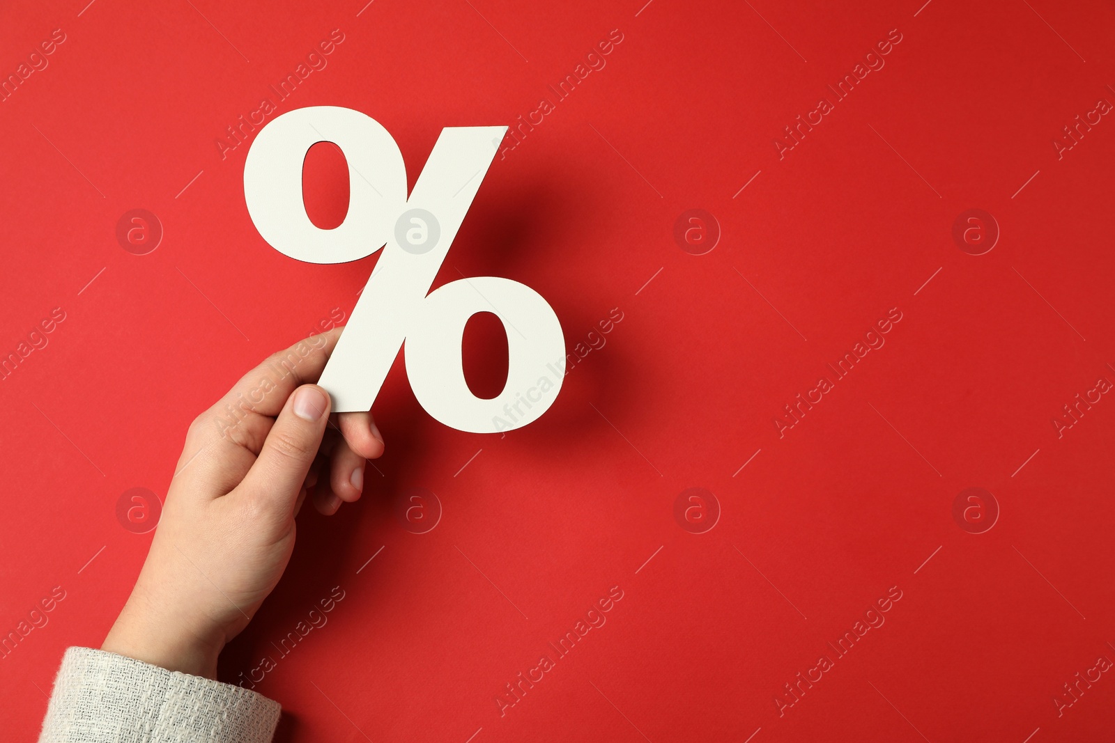 Photo of Man holding percent sign on red background, top view. Space for text