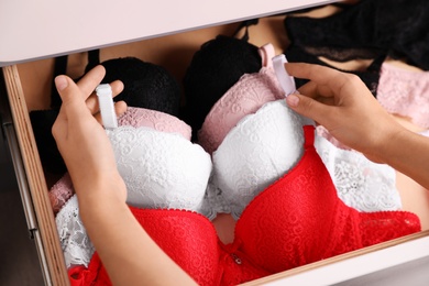 Woman taking bra out of drawer, closeup. Stylish underwear