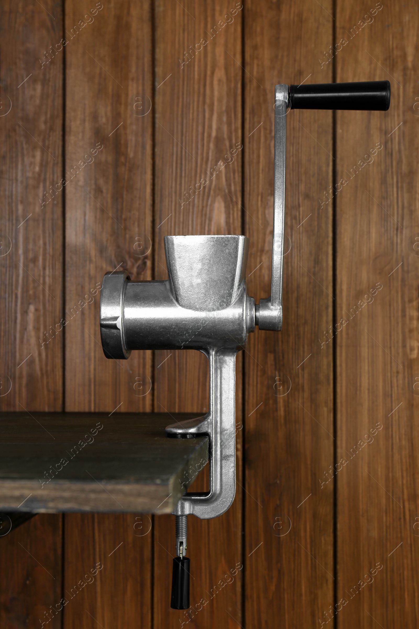 Photo of Metal manual meat grinder on table against wooden background