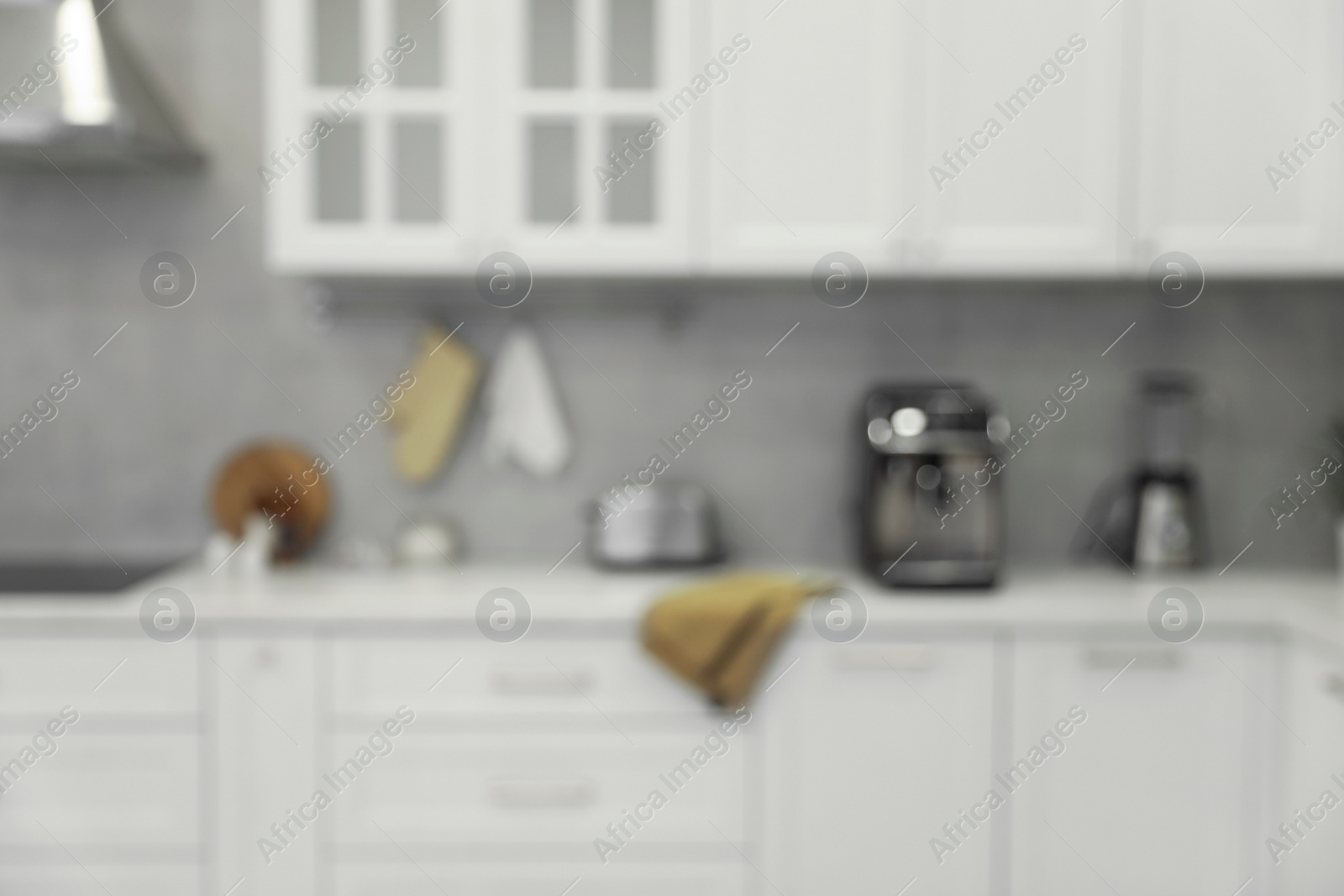 Photo of White stylish kitchen with furniture, blurred view. Interior design