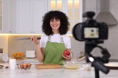 Photo of Smiling food blogger explaining something while recording video in kitchen