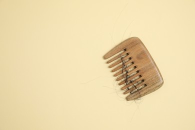 Photo of Wooden comb with lost hair on beige background, top view. Space for text