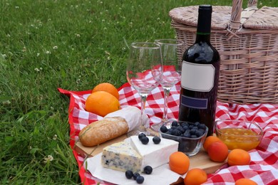 Photo of Picnic blanket with delicious food and wine outdoors on summer day