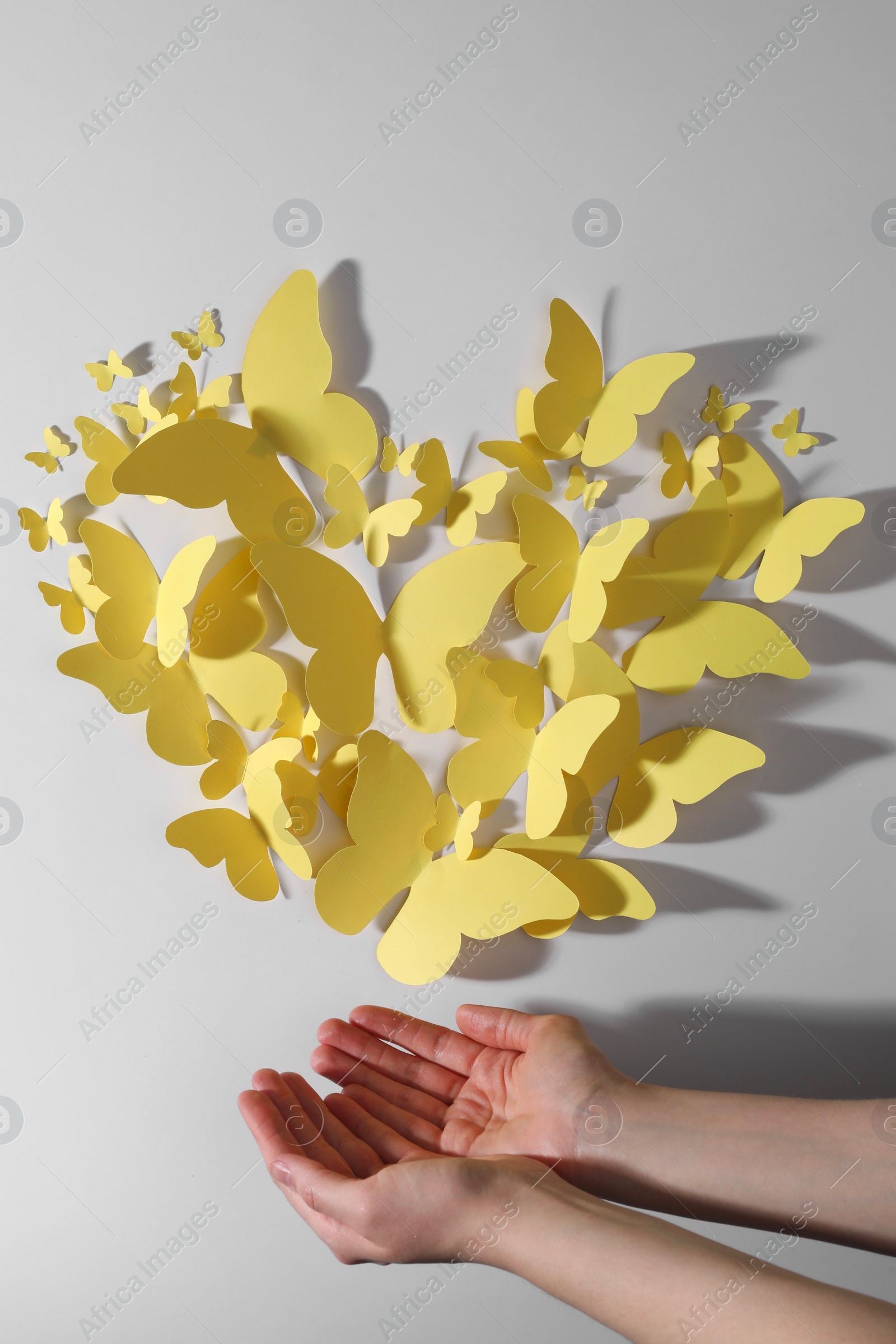 Photo of Woman with yellow paper butterflies on white background, top view