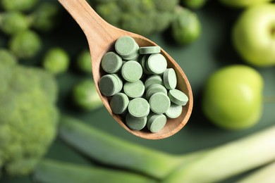 Photo of Wooden spoon with pills on blurred background, closeup. Prebiotic supplements