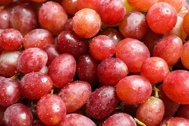 Photo of Fresh ripe juicy pink grapes as background, closeup view