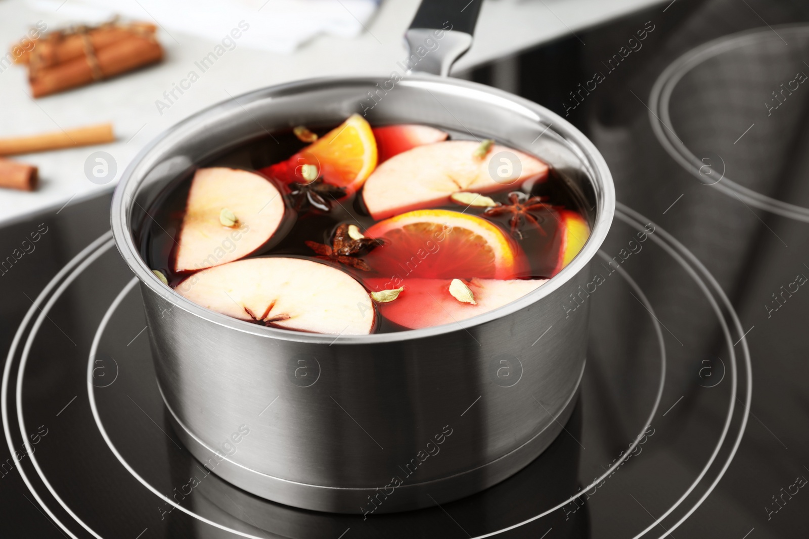 Photo of Delicious hot mulled wine in pot on stove, closeup