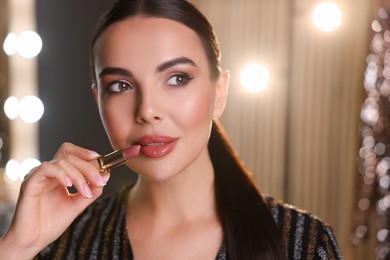 Bright makeup. Beautiful woman applying lipstick in dressing room