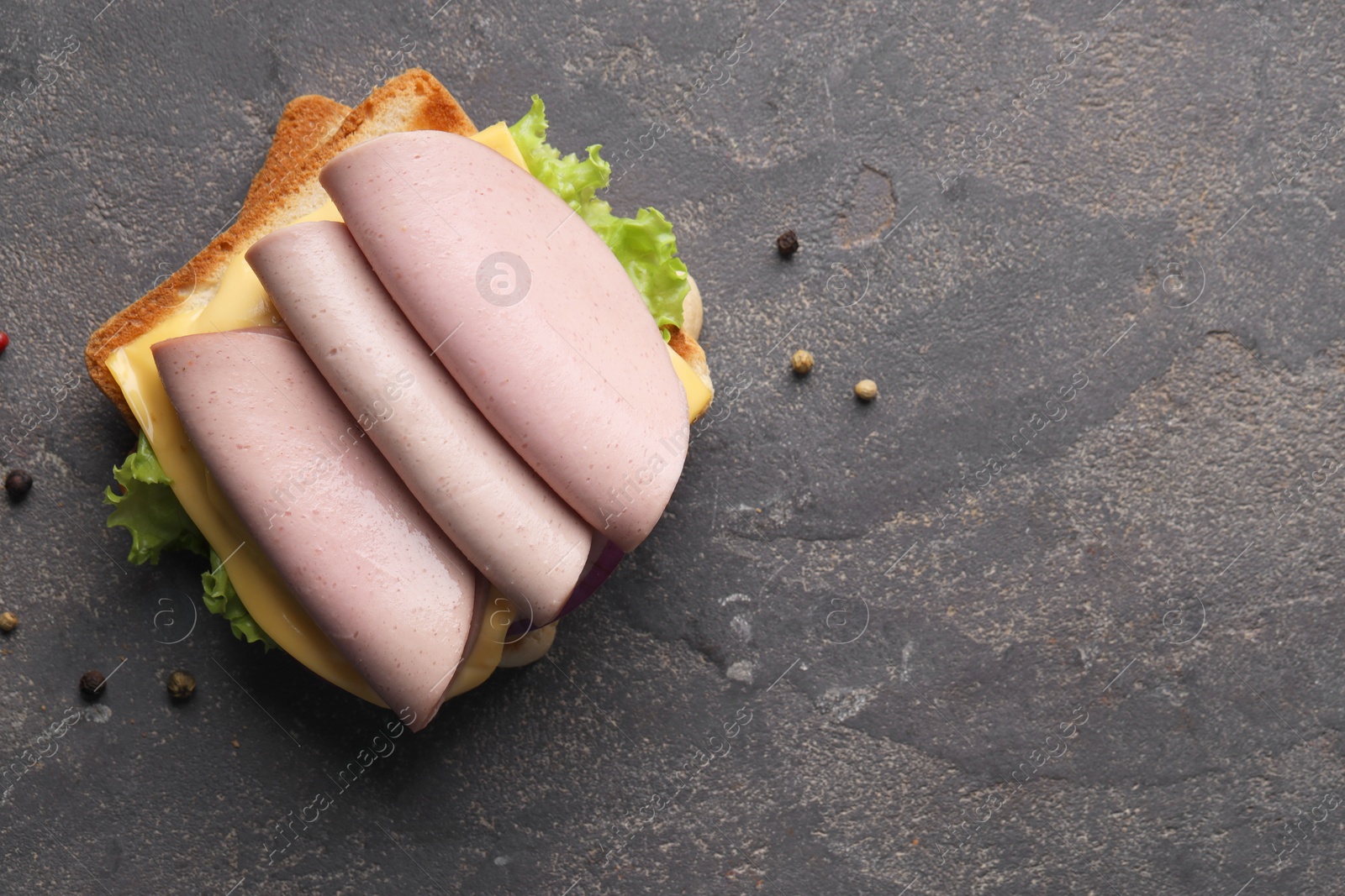 Photo of Delicious sandwich with boiled sausage and cheese on grey textured table, flat lay. Space for text
