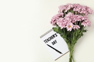 Photo of Flowers and notebook with words TEACHER'S DAY on white background, flat lay. Space for text