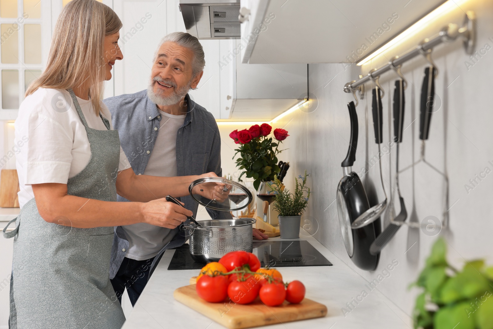 Photo of Affectionate senior couple cooking together in kitchen