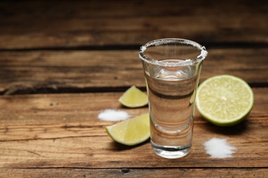 Photo of Mexican Tequila shot with salt and lime on wooden table. Space for text