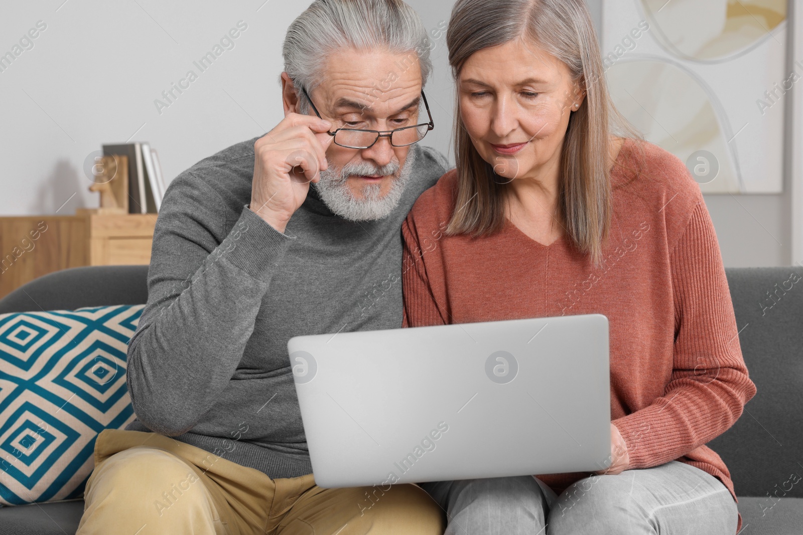 Photo of Elderly couple with laptop discussing pension plan in room