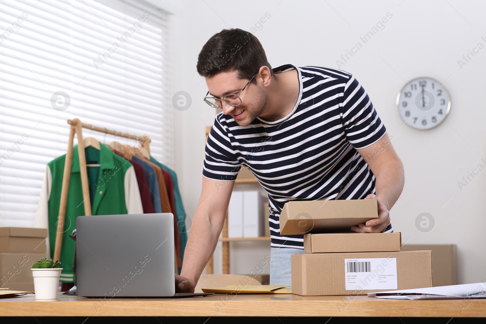 Photo of Seller with parcels and laptop working in office. Online store