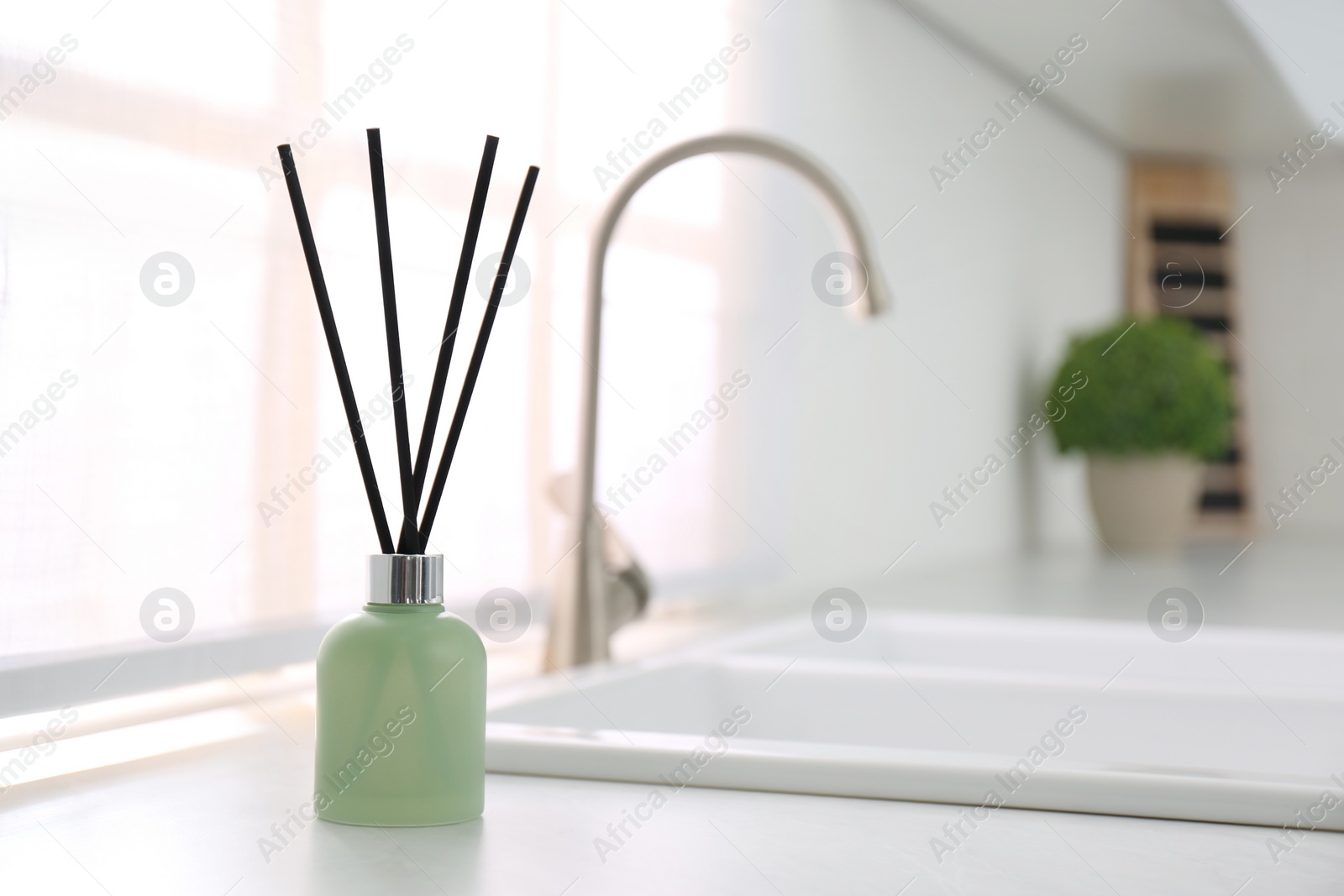 Photo of Aromatic reed air freshener on white table indoors. Space for text