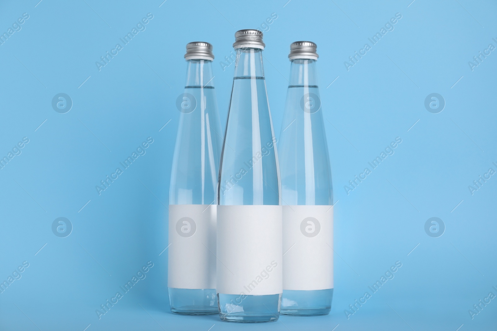 Photo of Glass bottles with soda water on light blue background