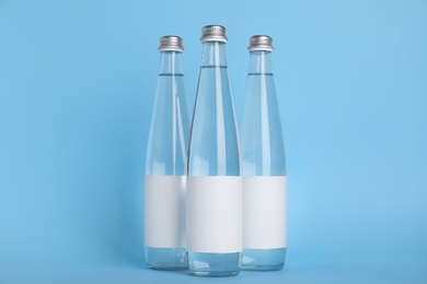 Glass bottles with soda water on light blue background