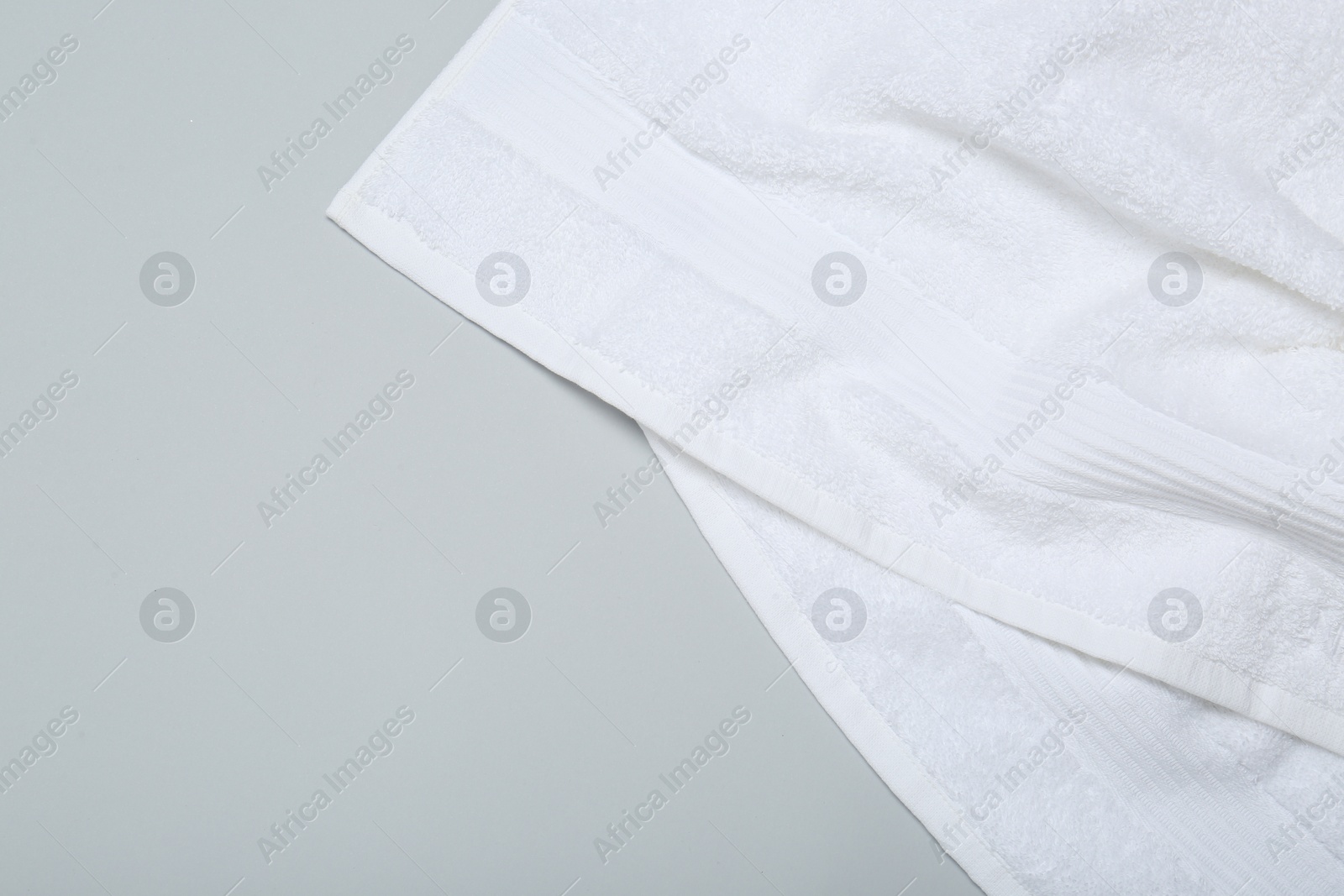 Photo of White terry towel on light grey background, top view. Space for text