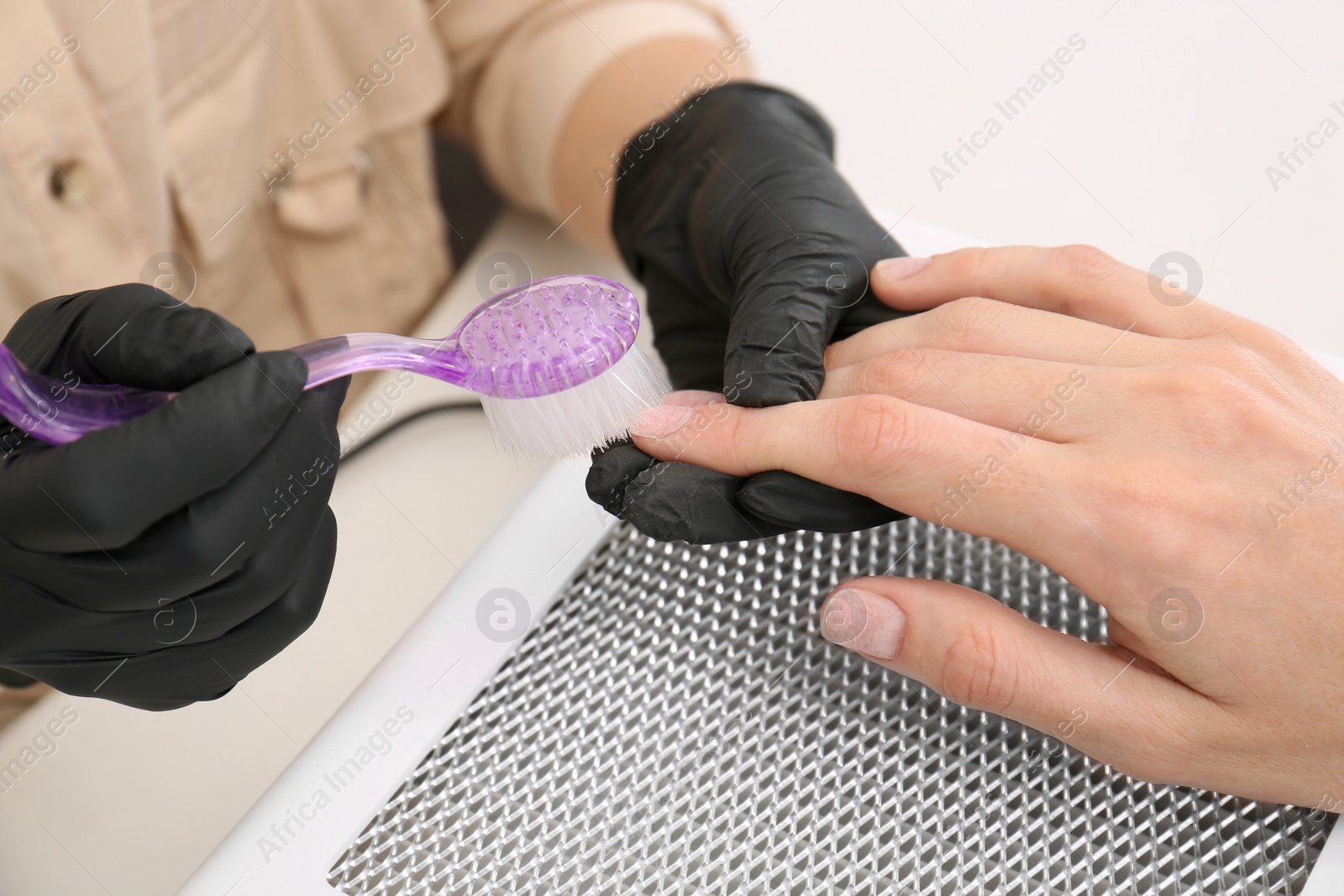 Photo of Professional manicurist working with client at white table, closeup