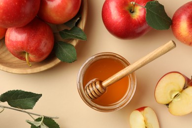 Delicious apples, jar of honey, leaves and dipper on beige background, flat lay