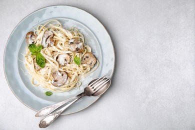 Photo of Delicious pasta with mushrooms on light grey table, top view. Space for text