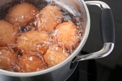 Photo of Chicken eggs boiling in pot on electric stove, closeup