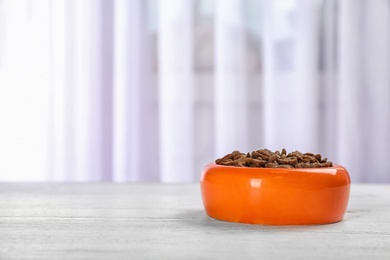 Photo of Bowl with food for cat or dog on floor. Pet care