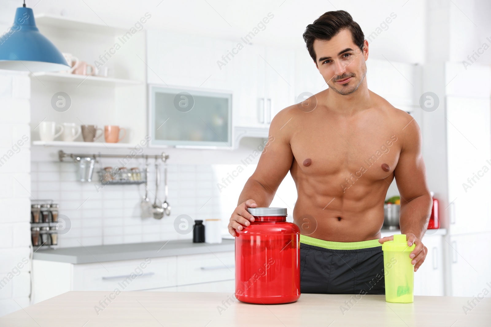 Photo of Young shirtless athletic man with protein shake powder in kitchen, space for text